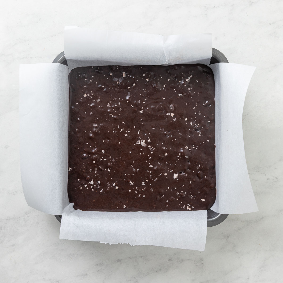 Brownie batter in a parchment lined pan.