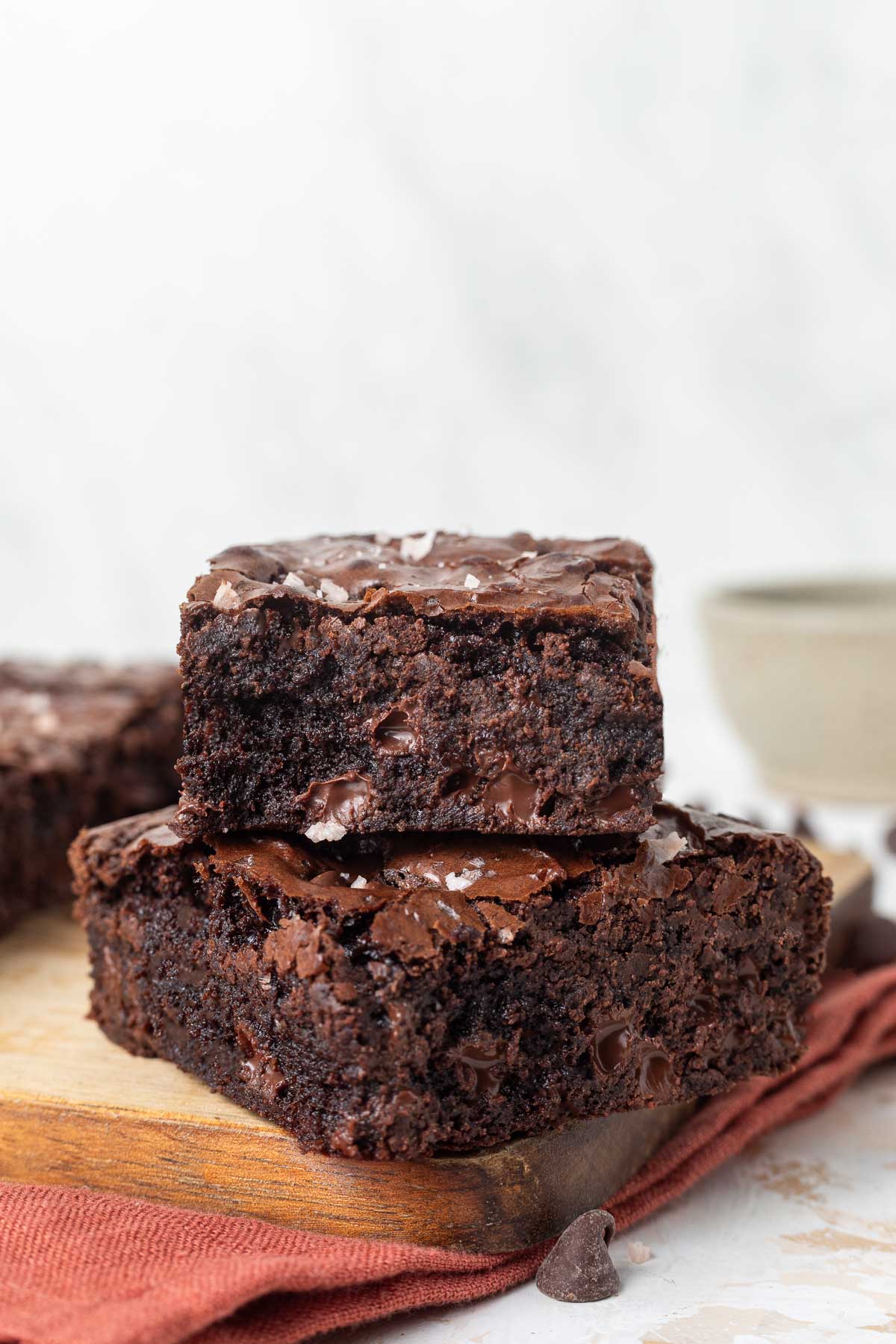 Two slices of chewy molasses brownies stacked on top of each other on a cutting board.