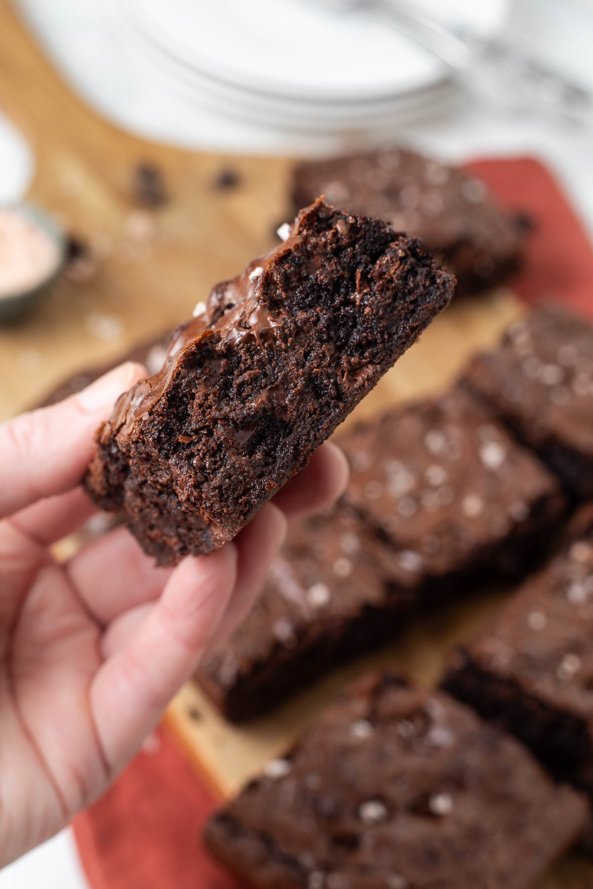 A hand holding up a slice of chewy brownie.
