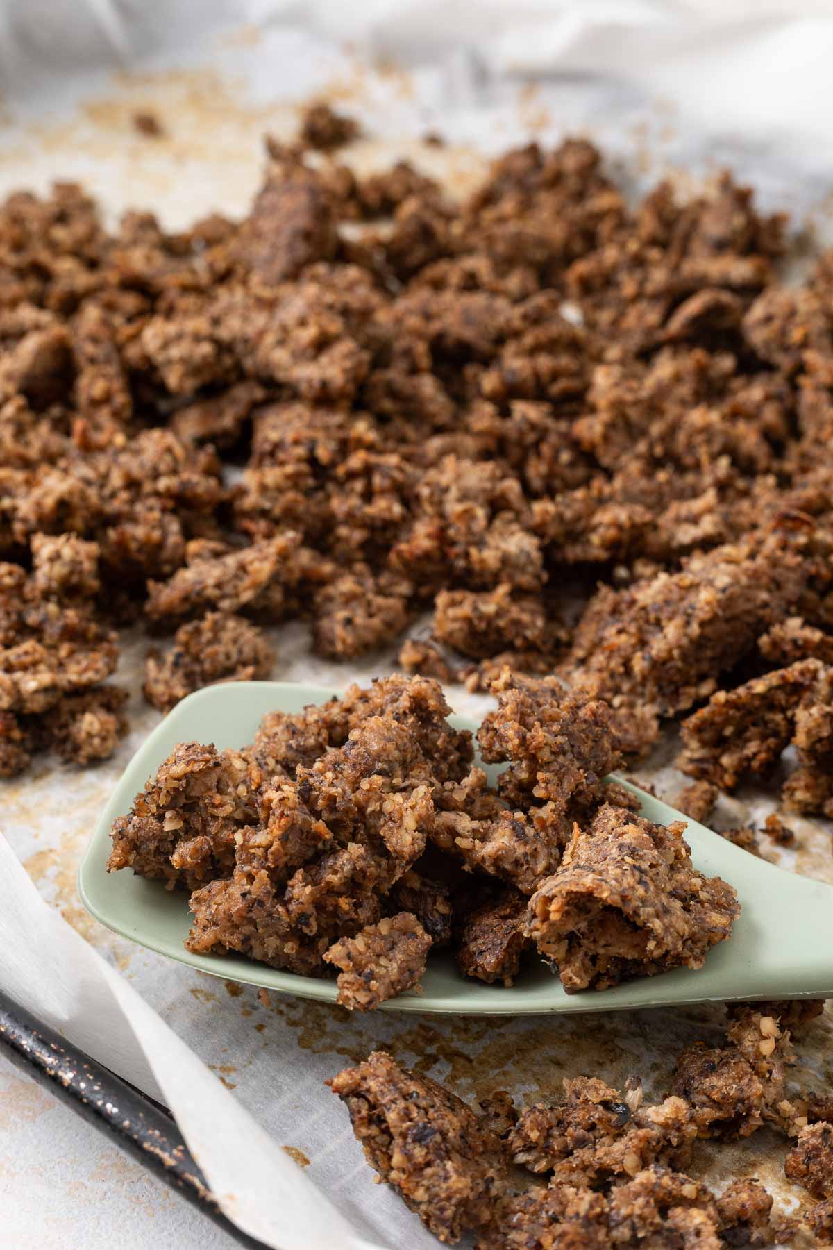 A sheet pan full of vegetarian ground beef with a spatula resting on it.