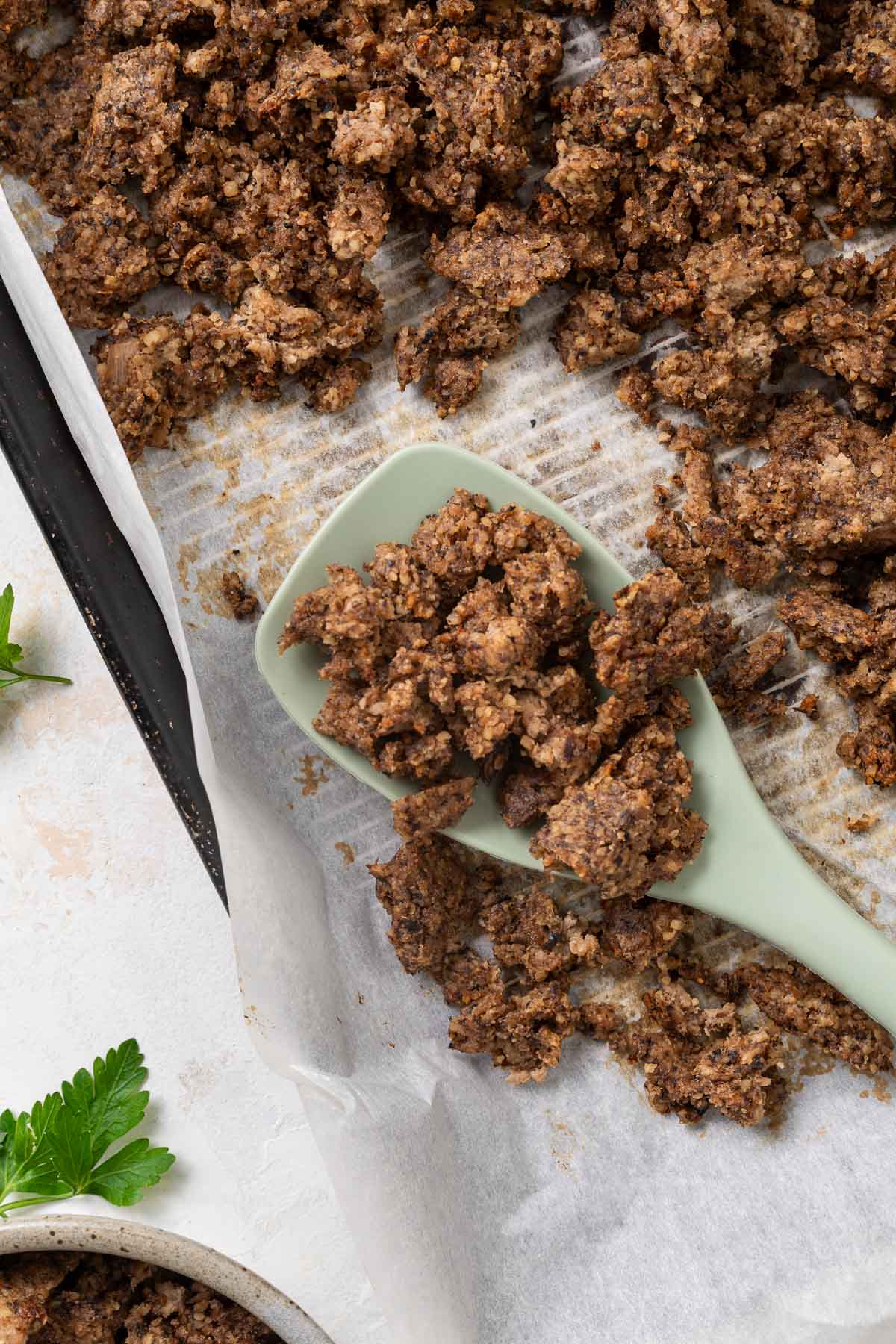 A sheet pan full of vegetarian ground beef with a spatula resting on it.