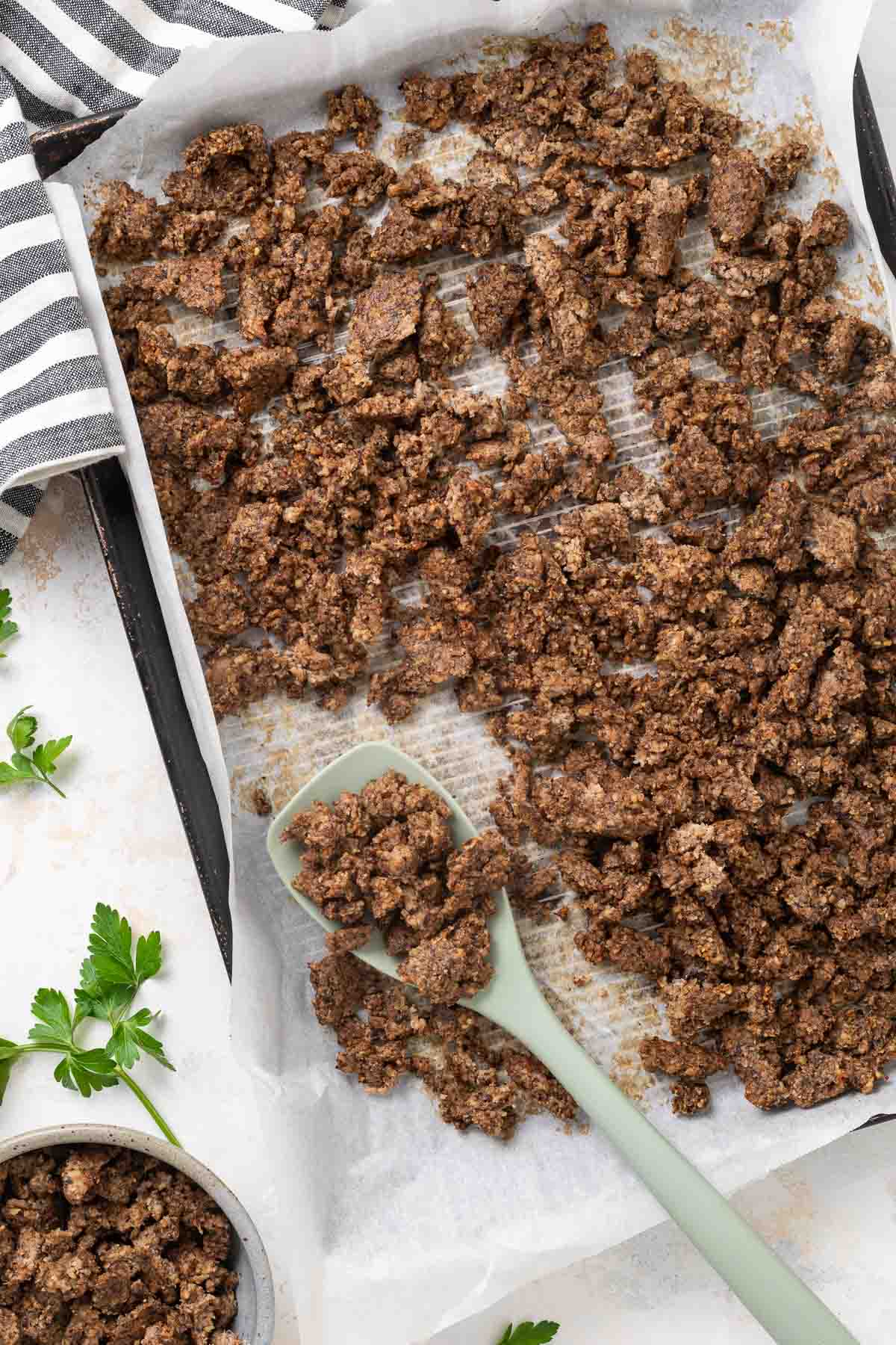 A sheet pan full of vegetarian ground beef with a spatula resting on it.
