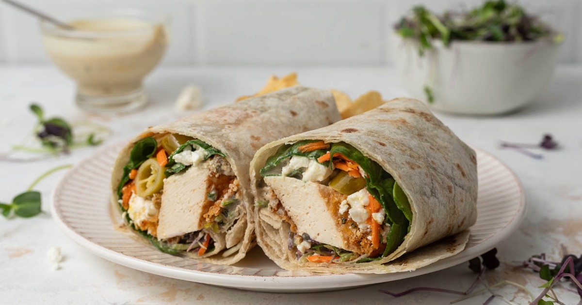 A crisp tofu wrap cut in half on a plate.