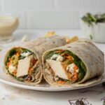 A crisp tofu wrap cut in half on a plate.