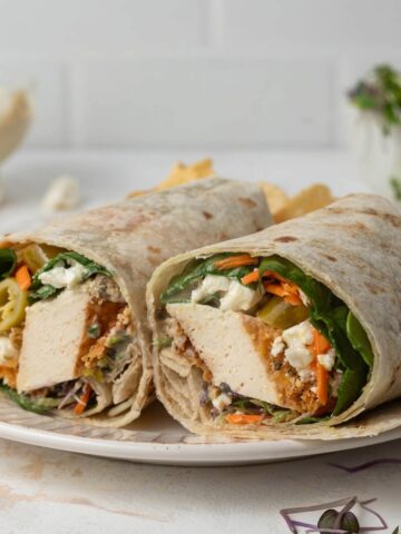 A crisp tofu wrap cut in half on a plate.