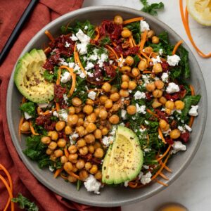 A large serving bowl of chickpea and kale salad on top of a red linen napkin.