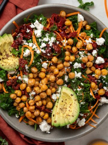 A large serving bowl of chickpea and kale salad on top of a red linen napkin.